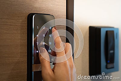 Closeup of a woman`s finger entering password code on the smart digital touch screen keypad entry door lock in front of the room Stock Photo