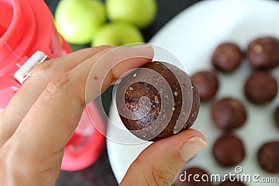 Closeup of woman`s hand whith healthy sweet treats. Cooking chocolate energy balls with almonds. Stock Photo