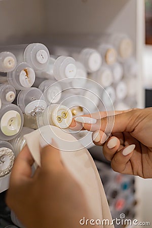 Closeup woman seamstress hands choosing button stud to tissue sample at store. Dressmaking Stock Photo