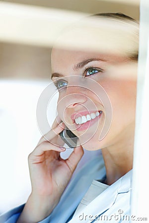 Closeup of a woman speaking on cellphone , view through glass. Closeup of a happy female having a conversation over the Stock Photo