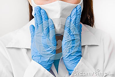 Closeup womans hands to the face in protective mask against coronavirus, SARS-CoV-2, 2019-nCoV or flu. Doctor in white labcoat, Stock Photo