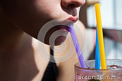 Closeup of womans lips drinking with pink straw. Woman drink cocktail. Close up wet sexy lips. Stock Photo