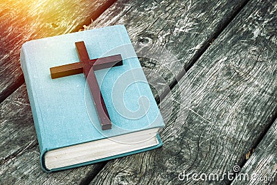 Closeup of wooden Christian cross on bible, burning candle and prayer beads on the old table. Stock Photo