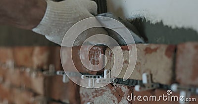 Closeup worker applying concrete glue to wall before applying brick tile Stock Photo