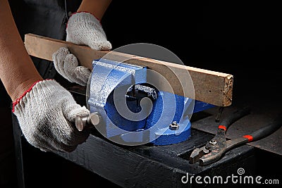 Workers hands on a wooden plank locked in the iron vise Stock Photo