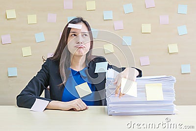 Closeup working woman are boring from pile of hard work and work paper in front of her in work concept on blurred wooden desk and Stock Photo