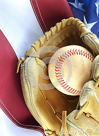 Closeup of worn baseball and mitt on a US flag background, great for America`s favorite pasttime. Vertical image. Stock Photo