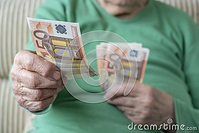 Wrinkled hand of a senior woman holding euro banknotes Stock Photo