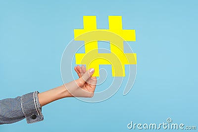 Closeup of yellow hash sign, female hand holding paper hashtag, symbol of social network trends and popular comments Stock Photo