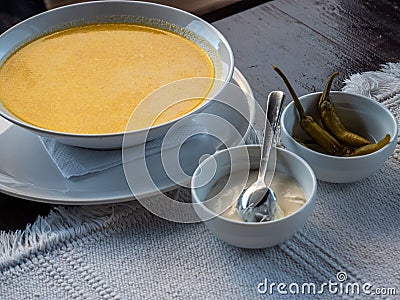 Closeup yellow puree soup in a white bowl, salted peppers and white sauce Stock Photo