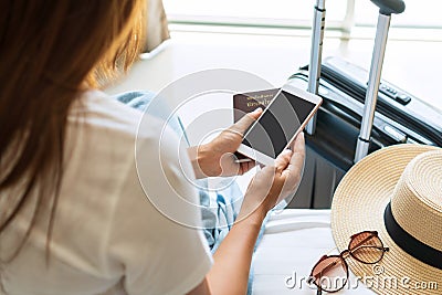 Closeup of young Asian traveler in white T- shirt holding passport and smartphone in hotel room after check in. Travel concept Stock Photo