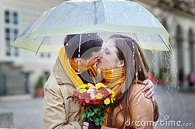 Closeup of young beautiful couple kissing under umbrella Stock Photo