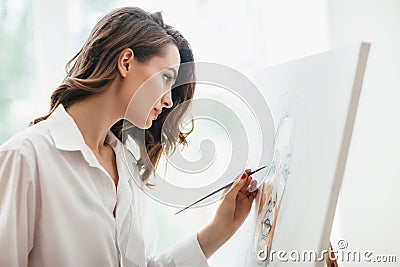 Closeup of young beautiful woman painting on canvas in studio Stock Photo