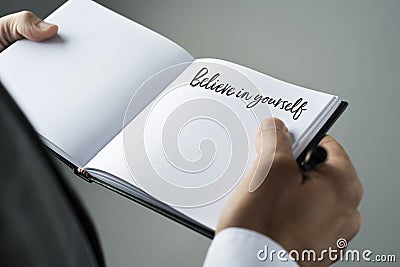 Man and notebook with the text believe in yourself Stock Photo