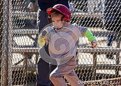 Closeup of a young child playing baseball running to first base after a hit Stock Photo