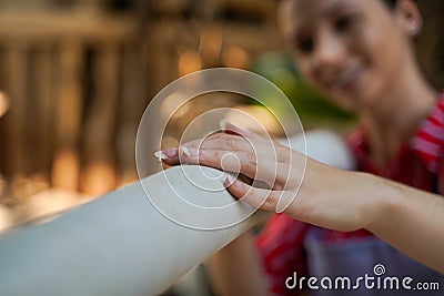 Closeup young female leather goods maker looking and touch leather roll for make products in workshop Stock Photo