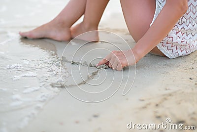 Closeup on young woman drawing on sand Stock Photo