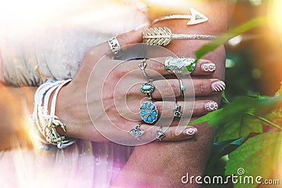 closeup of young woman hand and arm with lot of boho style jewrly, rings and bracelets outdoor light leak Stock Photo