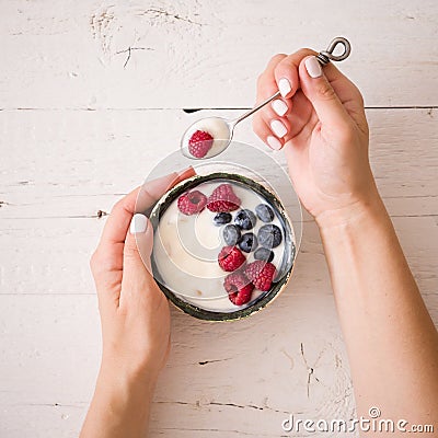 Closeup of Young woman hands with a bowl of yogurt. Girl eating organic yogurt for breakfast with fresh berries Stock Photo