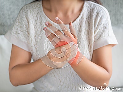 Closeup young woman sitting on sofa holds her wrist. hand injury Stock Photo