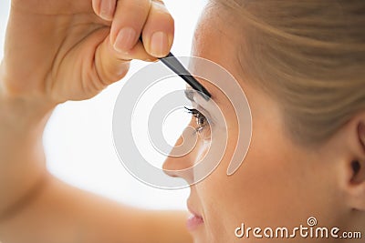 Closeup on young woman tweezing eyebrows Stock Photo