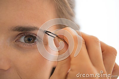 Closeup on young woman tweezing eyebrows Stock Photo