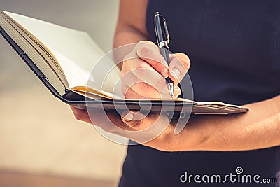 Closeup of young woman writing down letters in notepad for making note at her diary with her hand. Business and Lifestyle concept Stock Photo
