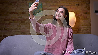 Closeupfors av kvinnliga tagande selfies för ung nätt brunettcaucasian på telefonen och lesammanträde på soffan in lager videofilmer Closeupfors av kvinnliga tagande selfies för ung nätt brunettcaucasian på telefonen och lesammanträde på soffan in lager videofilmer