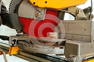 Closeupof mature sawing lumber with sliding compound miter saw , sawdust flying around Stock Photo