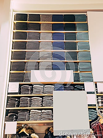 Clothes displayed in store. Copy spase for text. Lot warm sweaters of different color are neatly stacked in a row on the Stock Photo