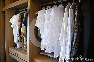 Clothes hang on a shelf in a designer clothes store, modern closet with row of cloths hanging in wardrobe, vintage rooms Stock Photo