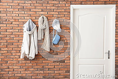 Clothes hanging on brick wall near door. Hallway interior Stock Photo