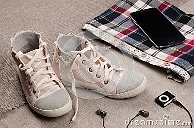 Clothing set. Womens sneakers and plaid shirt with lace insertion and black music player with headphones Stock Photo