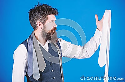 In clothing shop. Shop assistant offering wide choice of finest neckties. Bearded man choosing luxury necktie in Stock Photo