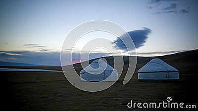 Cloud over the yurts at the shore of Song Kol Lake at the dawn, Kyrgyzstan Stock Photo