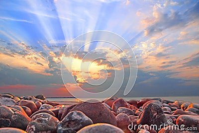 Cloudburst sun rays at sunset on whitstable beach Stock Photo