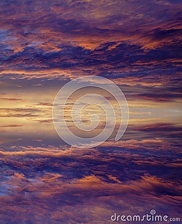 Clouds illuminated by the sun in the ev ening. Sunset Bright colors of the sky. Mirror symmetry of reflection. Stock Photo