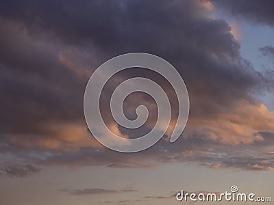 Cloudscape of gray-white thunderclouds in a blue sky with pink lights at sunset Stock Photo