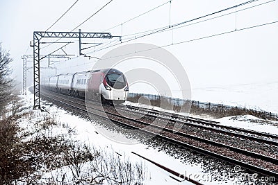 Cloudy foggy winter day view of Train on UK Railroad in England. Emma storm railway landscape. Stock Photo