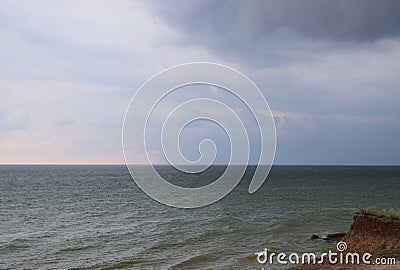 A cloudy grey sky shrouds the white foamy tipped teal waters of this beach Stock Photo