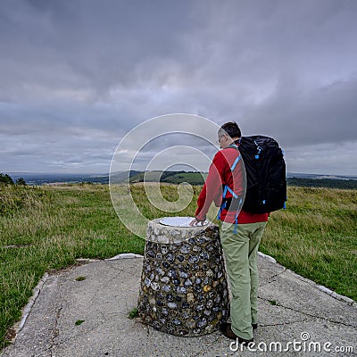 Cloudy overcast summer sunrise over the South Downs Way footpath from A middle aged male walker with backpack admiring the view Editorial Stock Photo