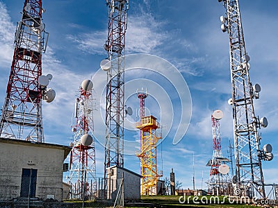 Cloudy sky behind telecommunication wireless towers with antennas Stock Photo