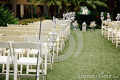 Cloudy tropical wedding venue - ceremony set up with white wooden trees, palm trees and vintage lanterns Stock Photo