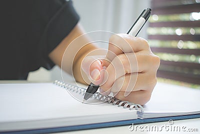 Clouse up. A hand pen writing on book near the window. Stock Photo