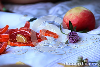 Clover flower, one red apple and lots orange marmalade slices. copy space Stock Photo