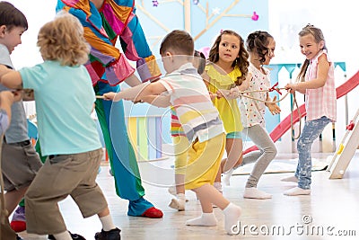 Clown entertains children at birthday party. Kids teams compete joyfully pulling rope Stock Photo