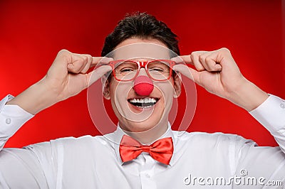 Clown in eyeglasses. Cheerful man with clown nose touching his e Stock Photo