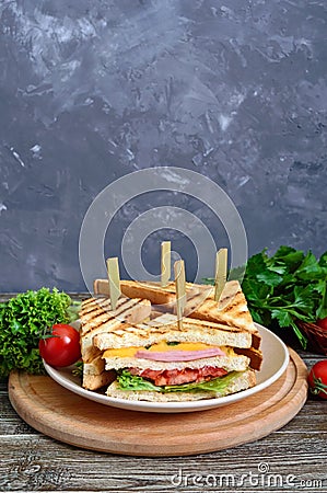 Club-sandwiches with crispy toast, sausage, cheese, tomato, greens. Stock Photo