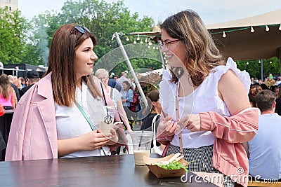 Two beautiful young girls talking at a fast food table Editorial Stock Photo