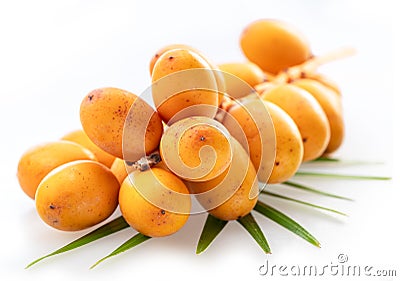 Cluster of yellow fresh dates, or date palm fruits lie on palm leaves isolated on white background. File contains clipping path Stock Photo